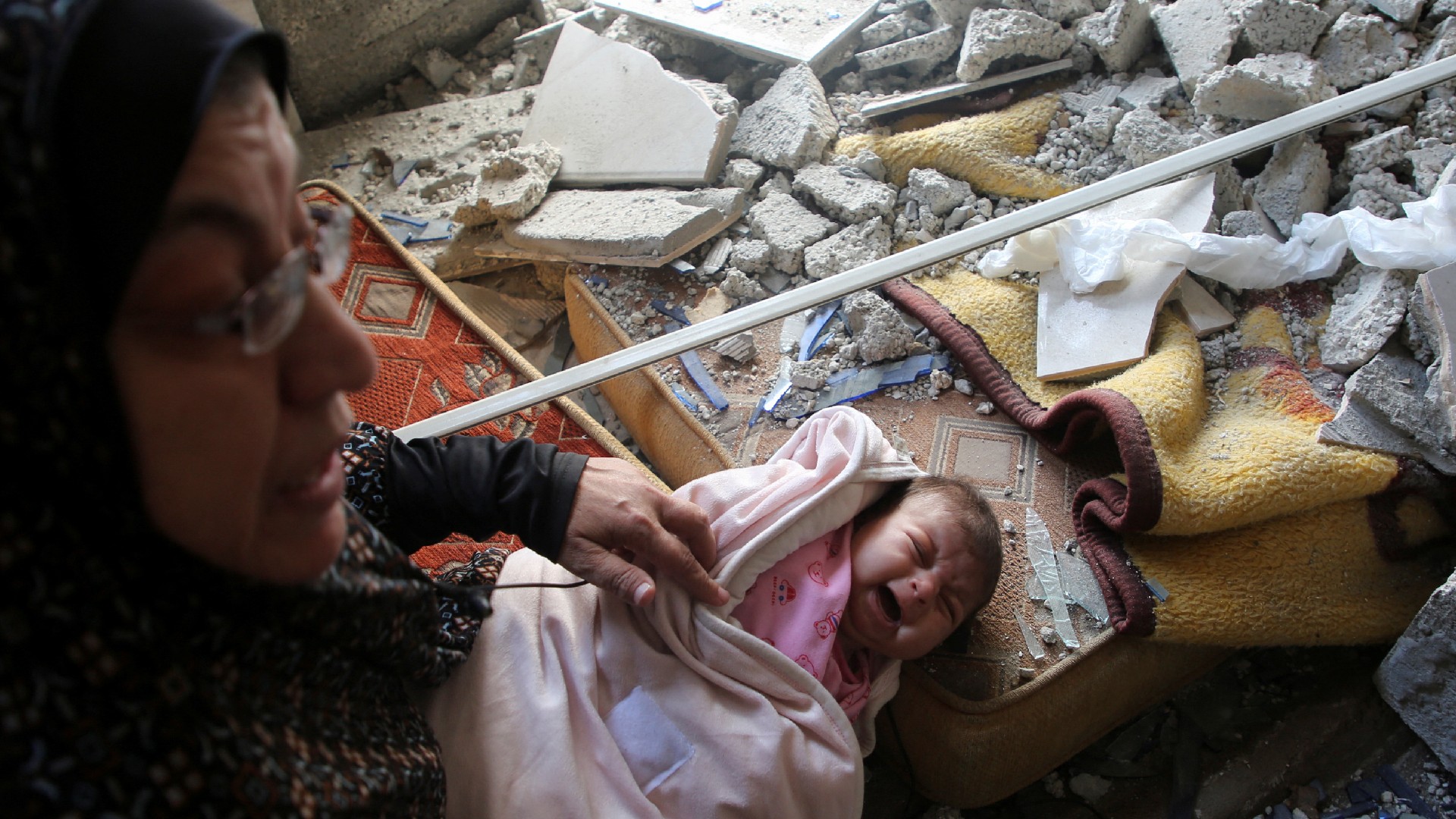 A baby cries in a damaged house at the site of an Israeli strike in Rafah, in the southern Gaza Strip, 29 April 2024 (Reuters)